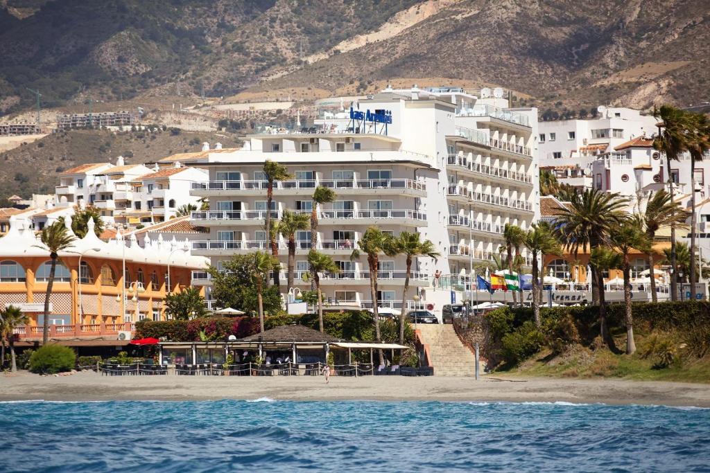 ein großes weißes Gebäude am Strand mit Palmen in der Unterkunft Hotel Las Arenas, Affiliated by Melia in Benalmádena
