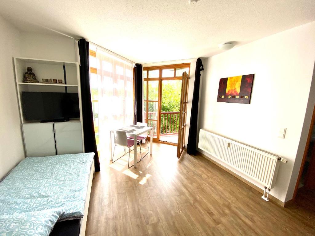 1 dormitorio con cama, mesa y balcón en Ferienwohnung Betty, en Rötz