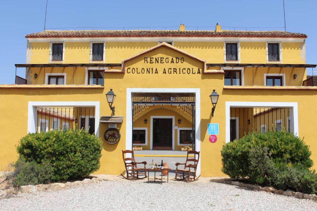 a yellow building with a table in front of it at Hotel rural Entreviñas in Caudete de las Fuentes