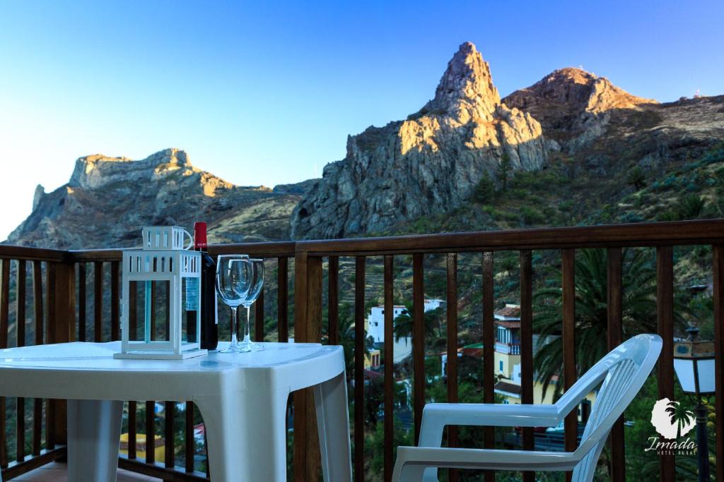 un tavolo e sedie su un balcone con un bicchiere di vino di Hotel Rural Imada a Imada