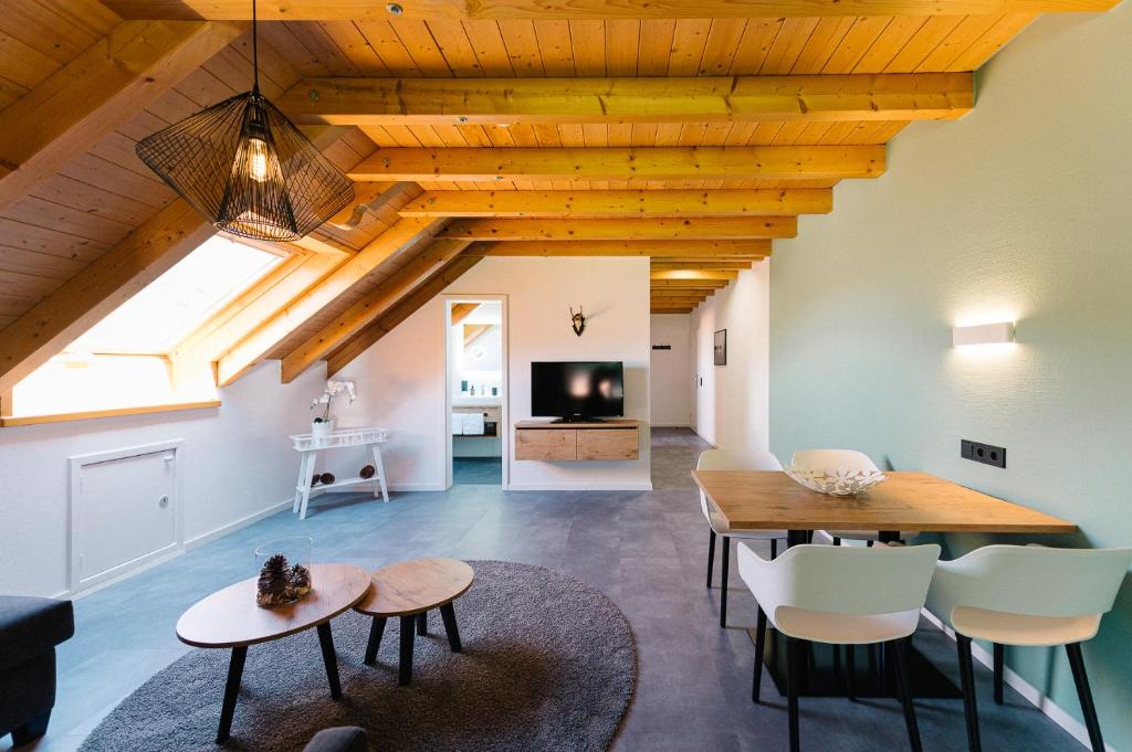 a living room with a wooden ceiling and a table and chairs at Moderne 2 Zi.-FeWo BlackForestArt Nähe Freiburg in Simonswald