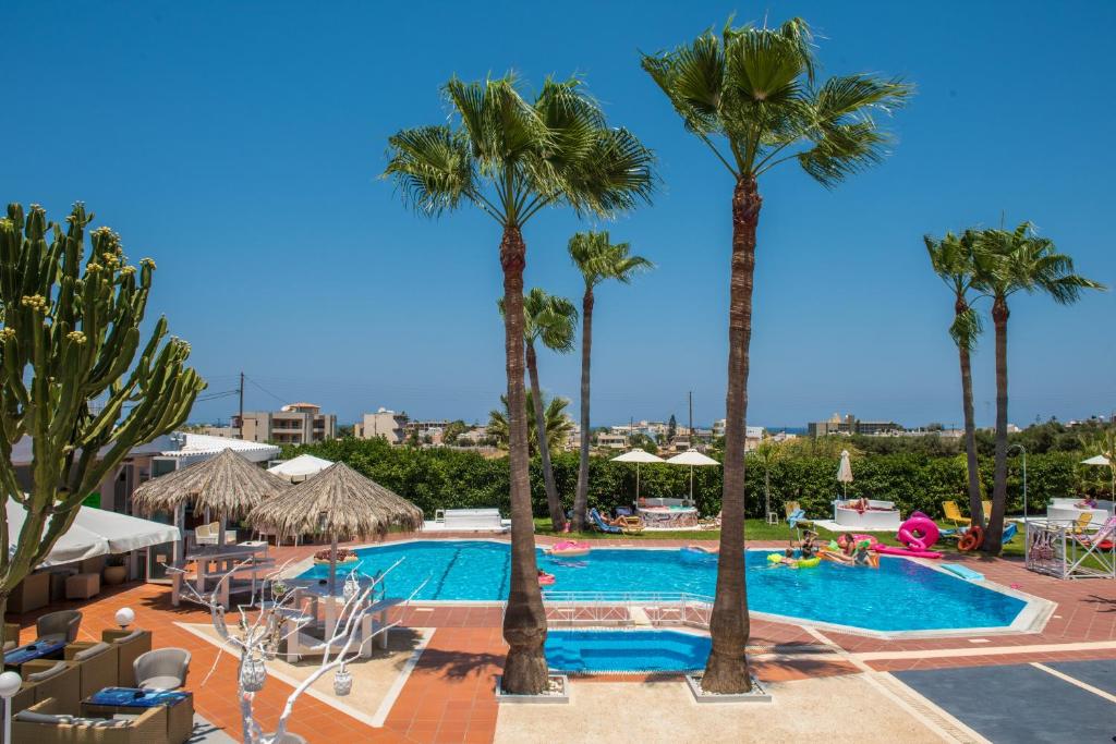 a swimming pool with palm trees in a resort at I Candy Malia by Estia in Malia
