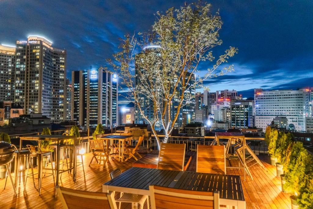 a rooftop patio with tables and chairs and a city skyline at Myeongdong Artmonstay in Seoul