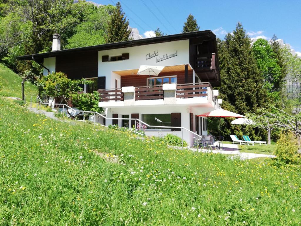 a house on the side of a hill with a field at Chalet Waldrand in Inden