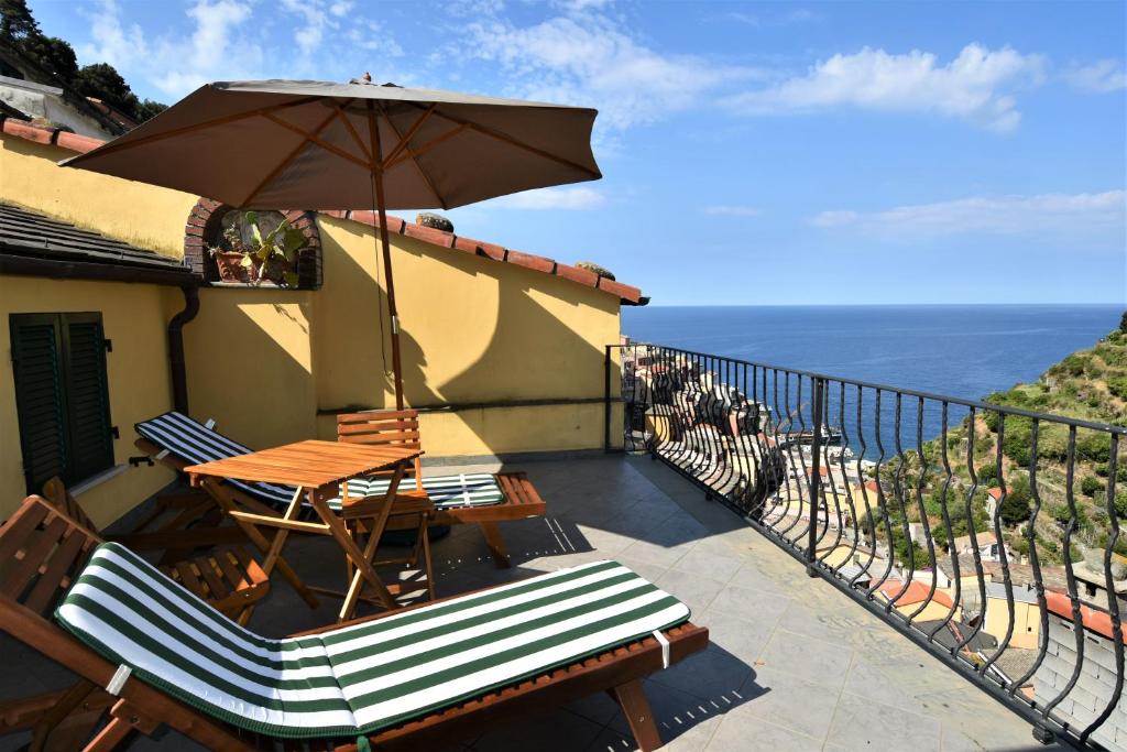 einen Balkon mit einem Tisch, Stühlen und einem Sonnenschirm in der Unterkunft Cà du Nilo in Manarola