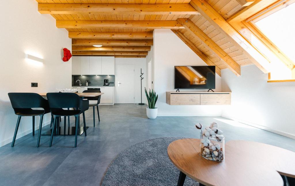 - un salon avec des plafonds en bois, une table et des chaises dans l'établissement Moderne 3 Zi.-FeWo BlackForestArt Nähe Freiburg, à Simonswald