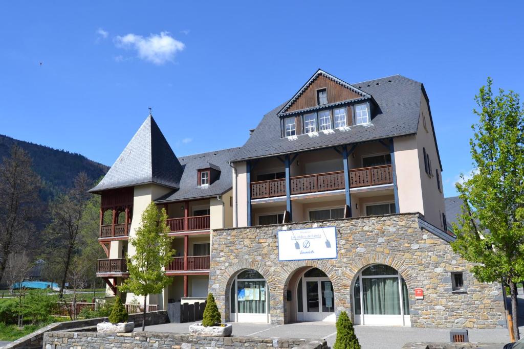un grand bâtiment avec un toit noir dans l'établissement Vacancéole - Les Jardins de Balnéa, à Loudenvielle