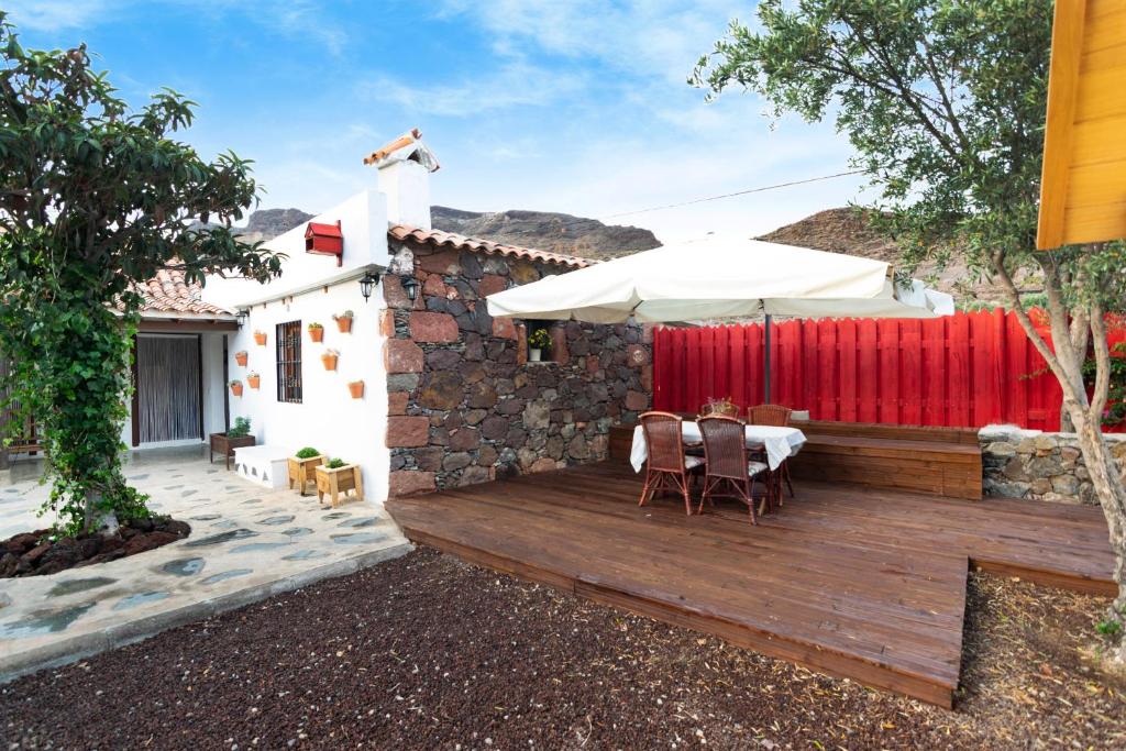 una terrazza in legno con tavolo e ombrellone di Mirador La Sorrueda a La Sorrueda
