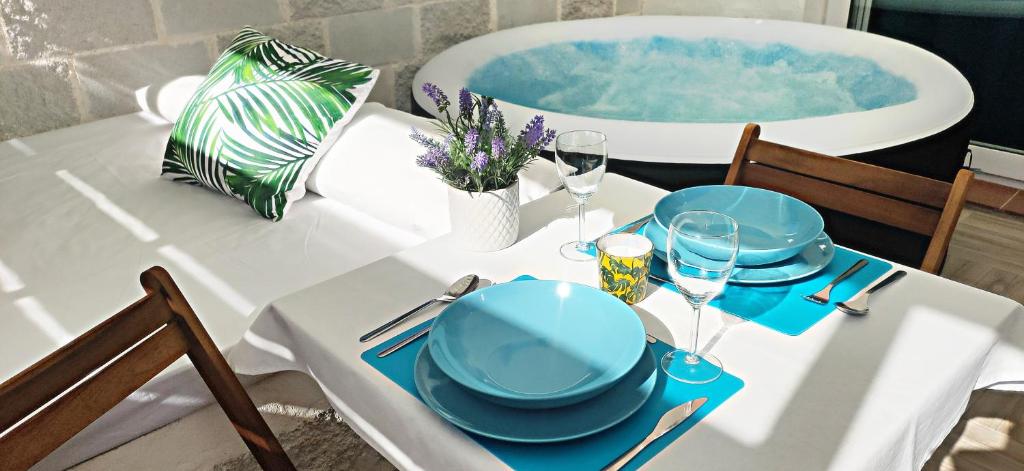 uma mesa com pratos e copos ao lado de uma banheira em La Calita Escondida - Jacuzzi y Cocina en Terraza Privada - Piscina y Parking Gratis em Chiclana de la Frontera