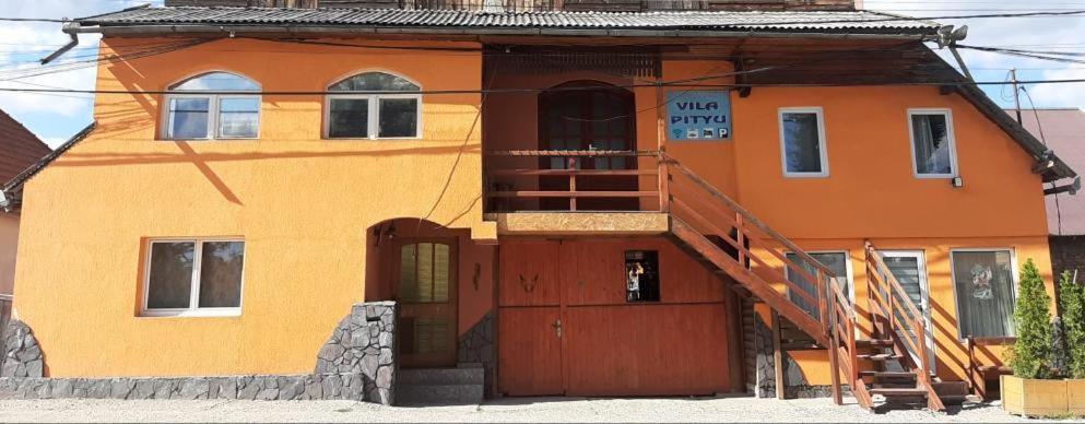 una casa naranja con puerta y escalera en Vila Pityu, en Subcetate