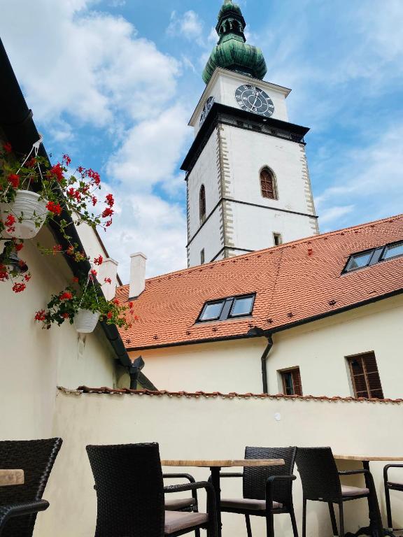 a clock tower on top of a building with chairs at Demaris in Třebíč