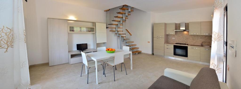 a kitchen and dining room with a white table and chairs at Le Villette di Capo Testa in Santa Teresa Gallura
