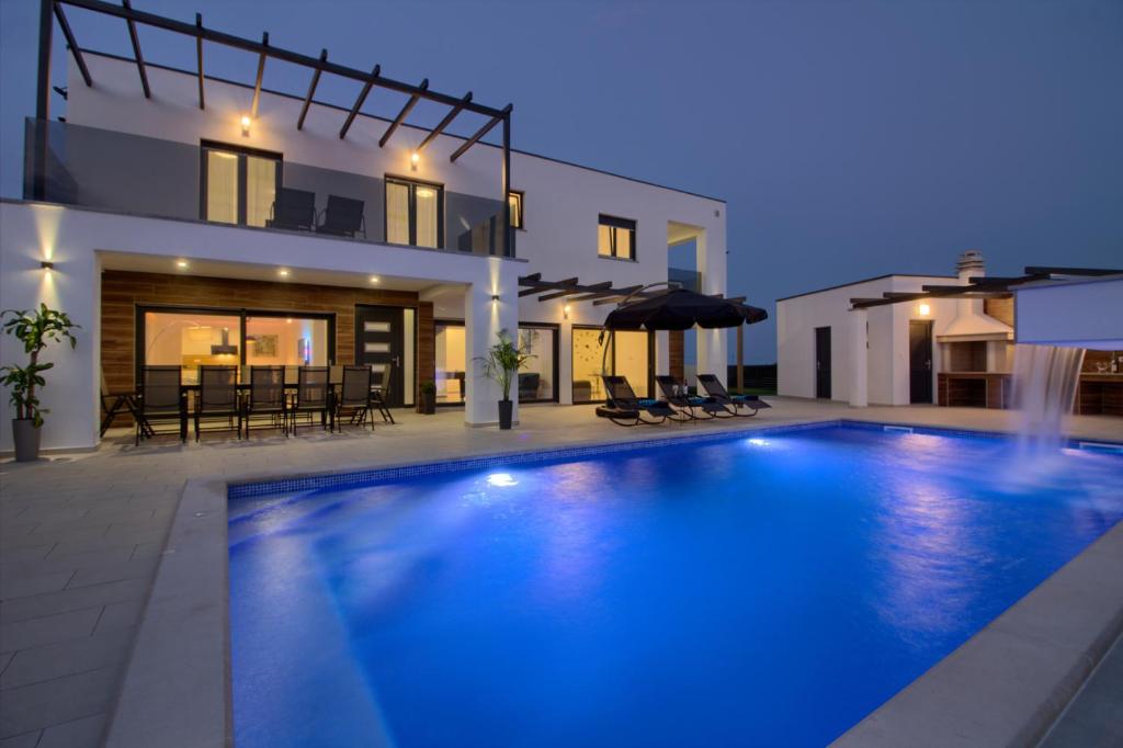 a swimming pool in front of a house at night at New luxury Villa with extra heated pool with hydromassage, biliard near town center in Marčana