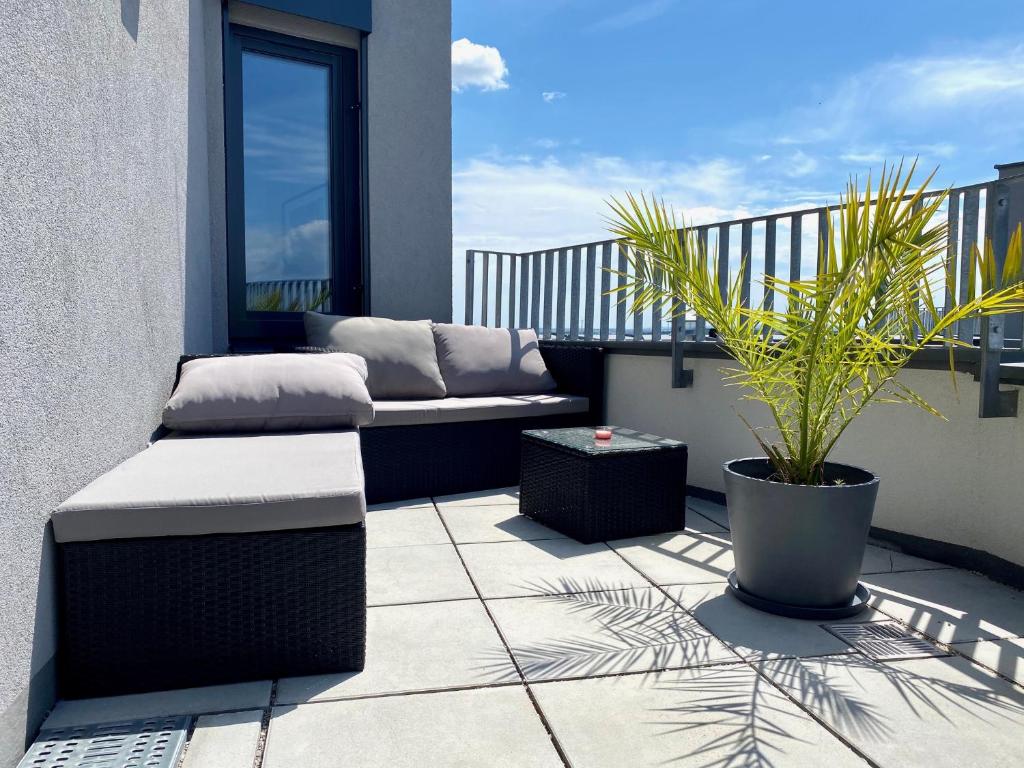 a patio with a couch and a plant on a balcony at Sonnenwohnen Penthouse direkt bei U-Bahn und Therme Wien mit Top Anbindung ins Zentrum in Vienna