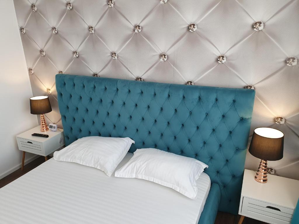 łóżko z niebieskim zagłówkiem i 2 stolikami nocnymi w obiekcie ARISTOCRAT CENTRAL w mieście Târgu Jiu