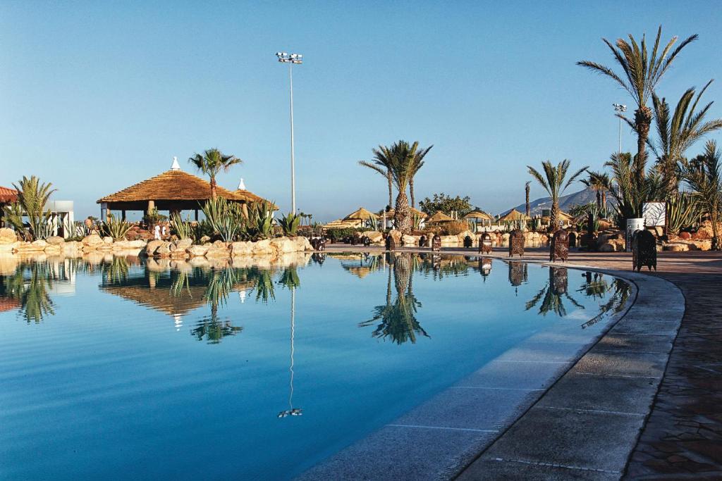 uma piscina de água com palmeiras num resort em Hotel Riu Tikida Dunas - All inclusive em Agadir