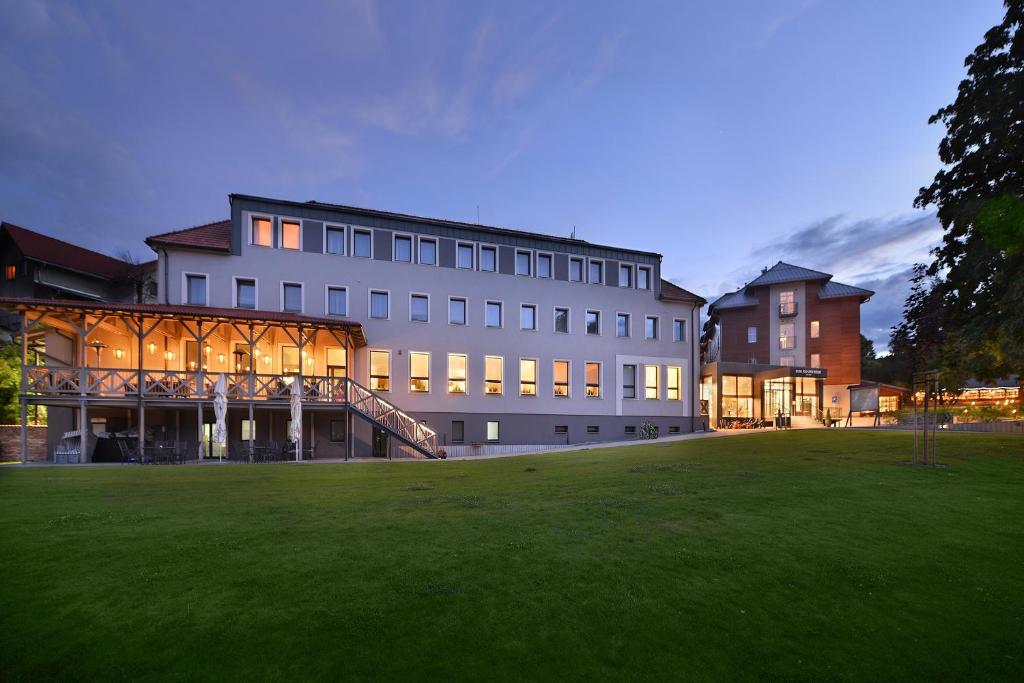 a large building with a lawn in front of it at Hotel pod Lipou RESORT in Modra