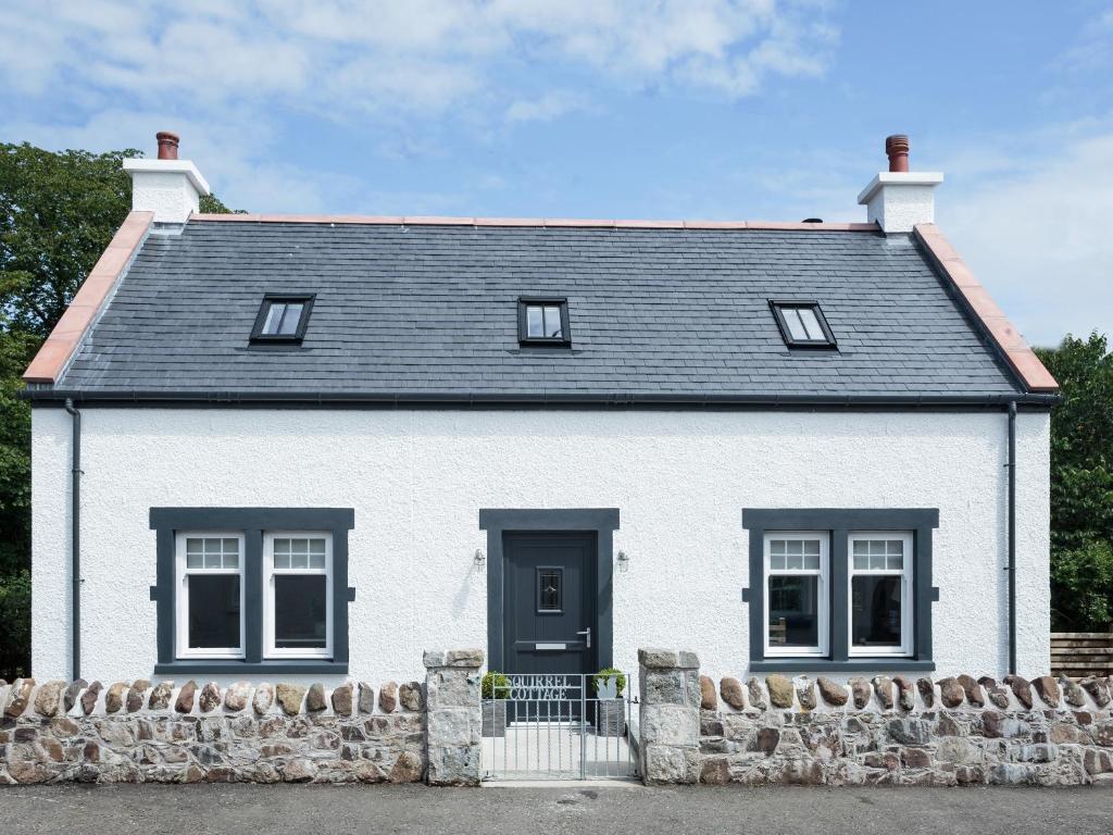 a white house with a stone wall at Squirrel Cottage in Stranraer