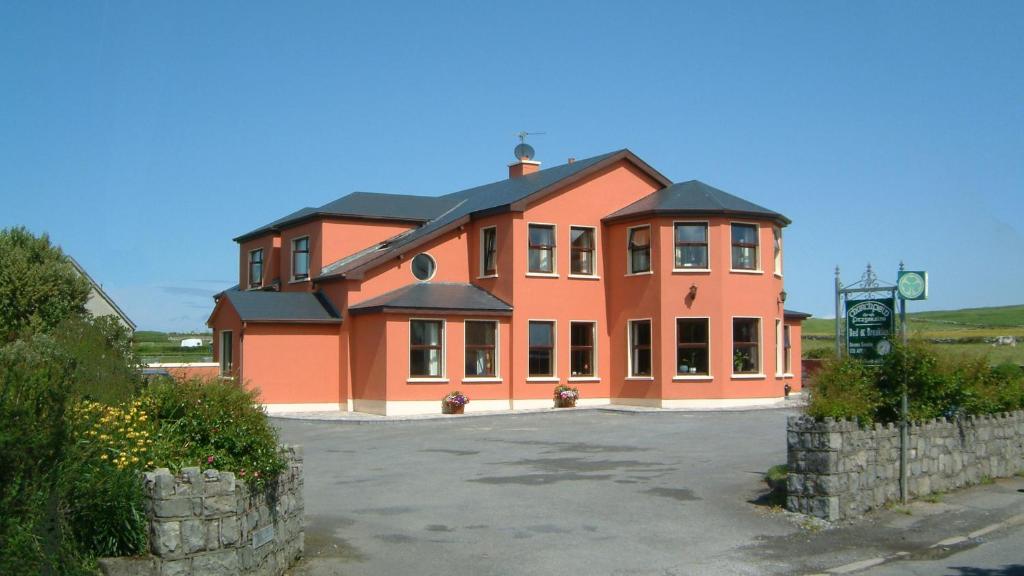 una grande casa arancione con molte finestre di Churchfield B&B a Doolin