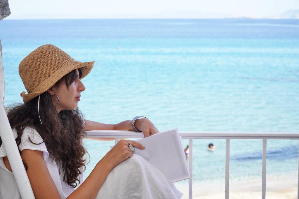 a woman sitting in a chair at the beach at Moutsouna Beach in Moutsoúna