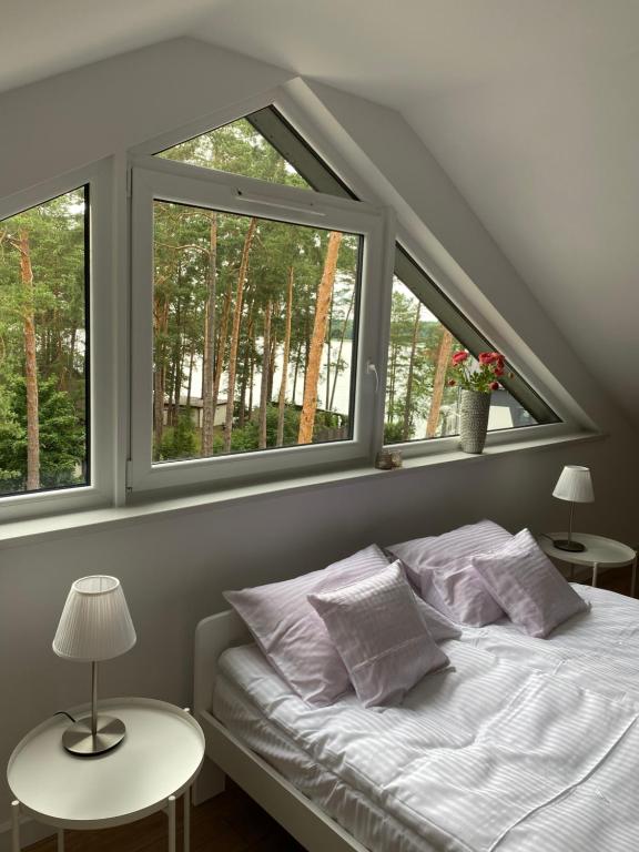 a bedroom with a bed with two windows at Apartament Meralia in Augustów