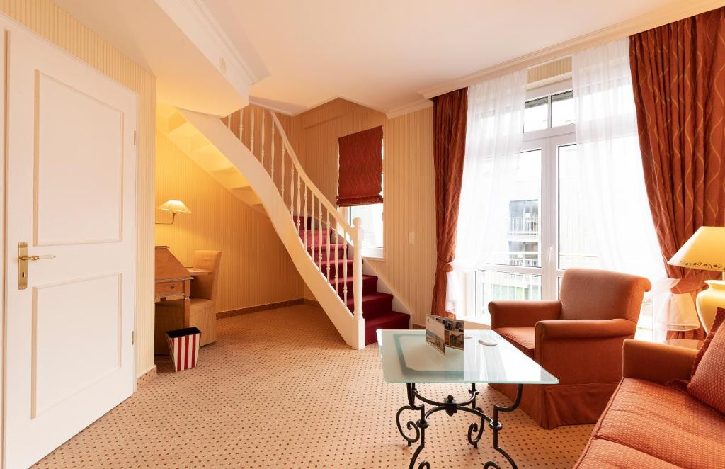 a living room with a staircase and a couch and a table at Strandhotel Sylt Westerland in Westerland