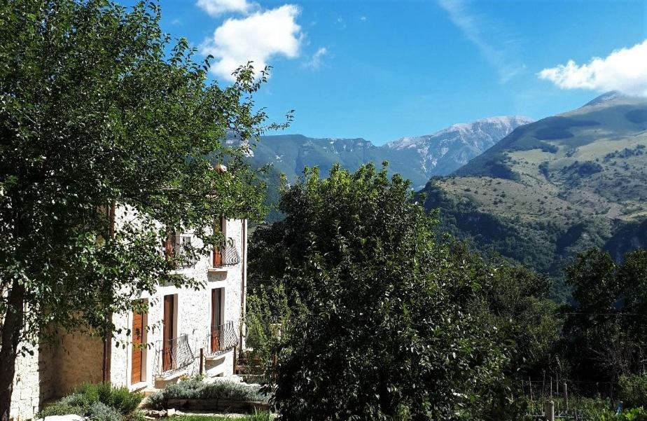 a white building with trees and mountains in the background at Majellame in Caramanico Terme