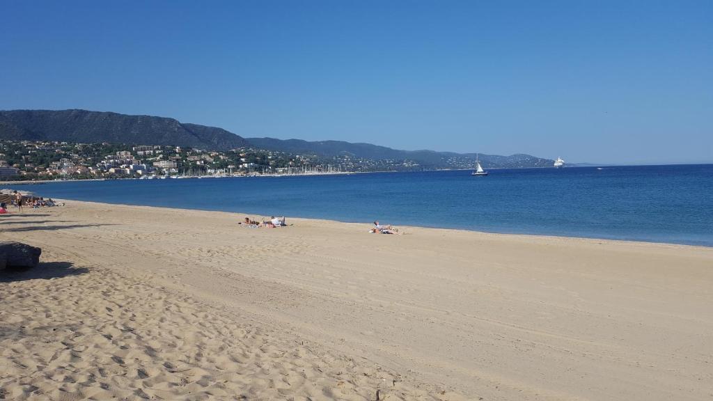 uma praia com pessoas deitadas na areia e na água em tahiti parc maisonnette 6 pers 2 chambre em Le Lavandou