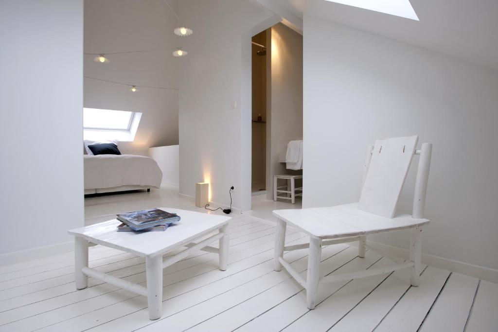 a white living room with a chair and a table at La Maison Haute guesthouse in Brussels