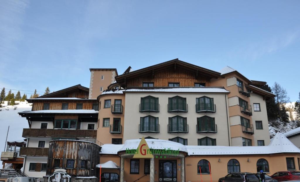 een groot gebouw tegenover een skigebied bij Hotel Grünwaldkopf in Obertauern
