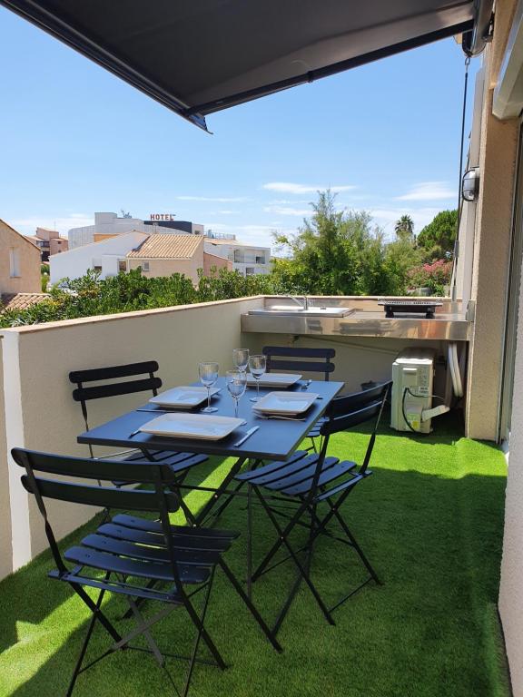 niebieski stół i krzesła na balkonie z trawą w obiekcie T2 Bis Design et Lumineux à 200m du Village Naturiste w Cap d'Agde