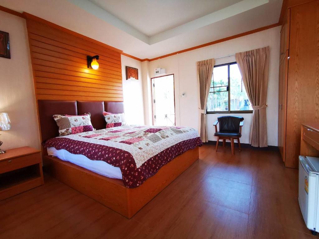 a bedroom with a large bed and a chair at RS Phong Riverside Resort in Khon Kaen