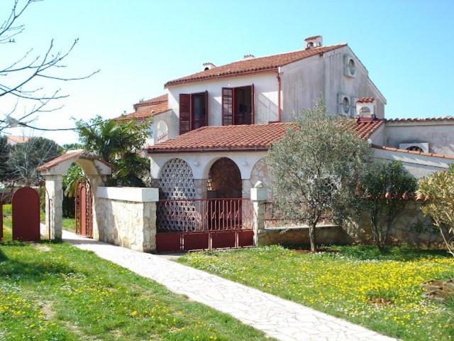 a house with a red gate in a yard at Apartments Jelena in Peroj
