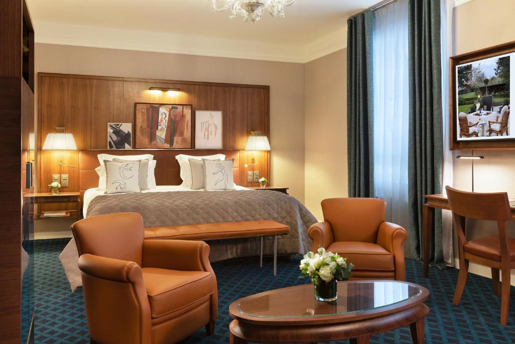a hotel room with a bed and chairs and a table at Hôtel Barrière Le Westminster in Le Touquet-Paris-Plage
