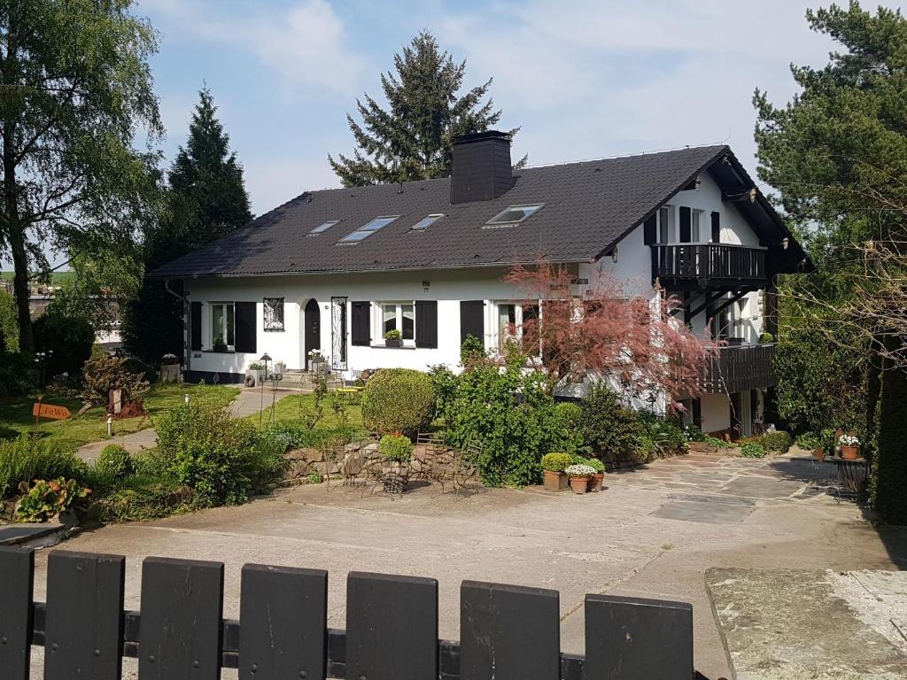 ein weißes Haus mit einem schwarzen Dach und einer Auffahrt in der Unterkunft Fewo am Wald in Balve