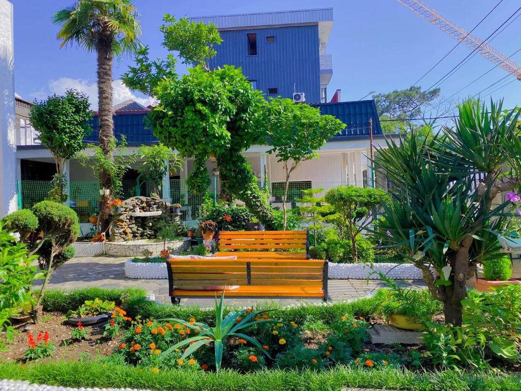 eine Holzbank in einem Garten mit Blumen in der Unterkunft Villa NiNo in Kobuleti