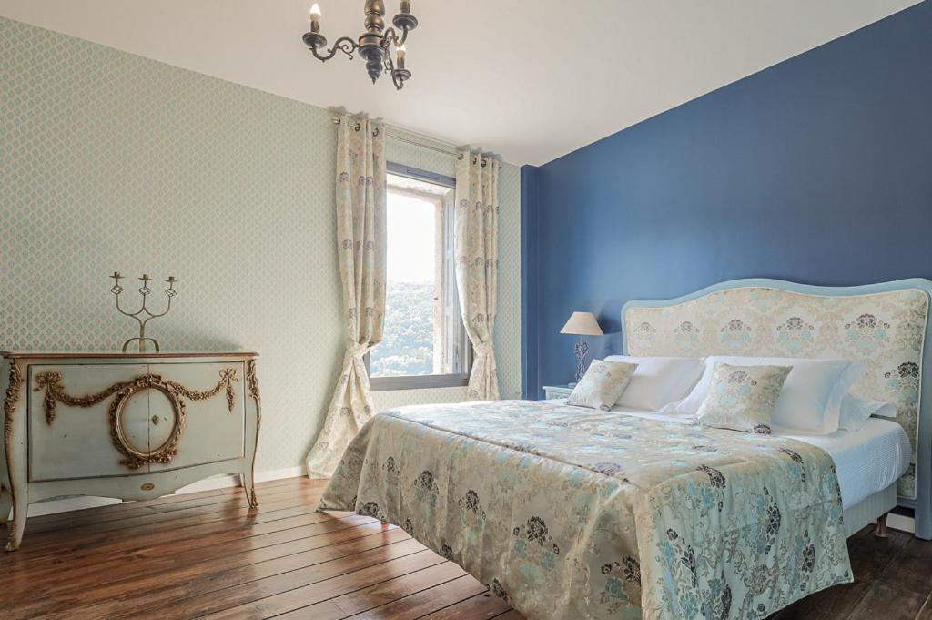 Dormitorio azul con cama y ventana en Le Relais Des Chartreuses, en Le Boulou