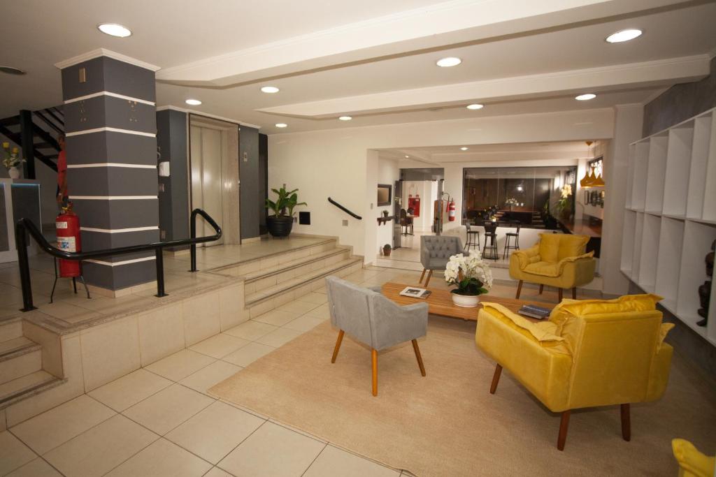 a living room with yellow chairs and a table at Láparos Hotel in São Carlos