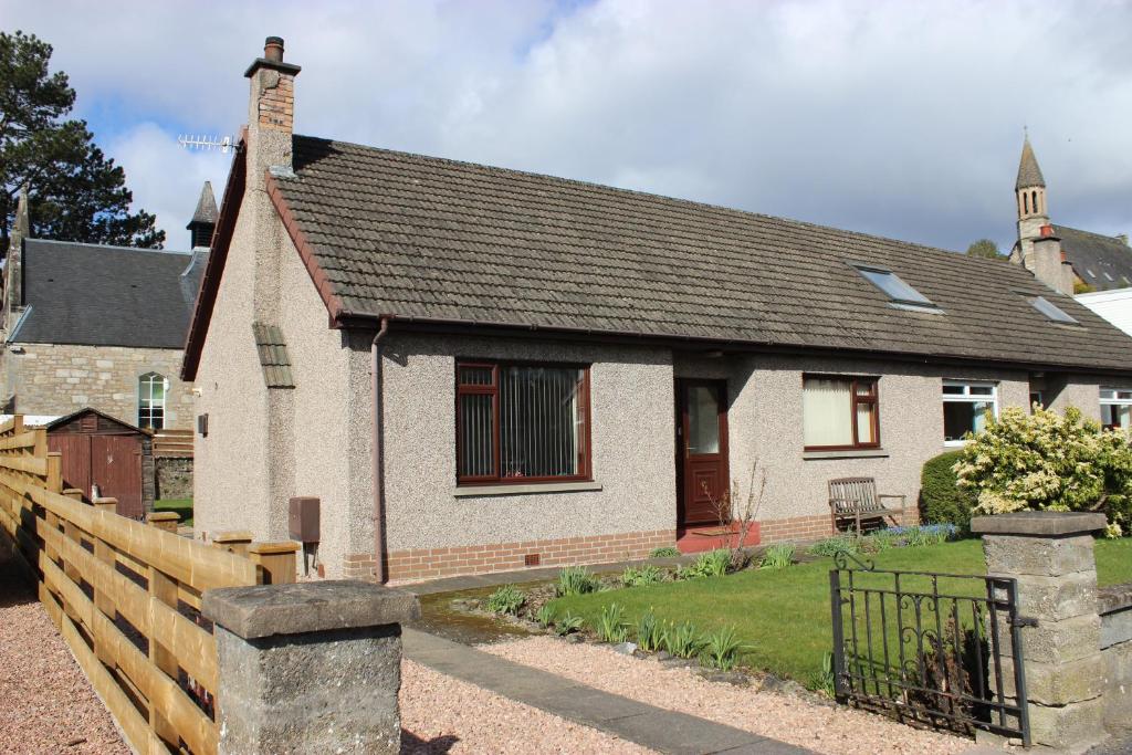 una piccola casa con una recinzione di fronte di Newholme Self-Catering Bungalow a Pitlochry