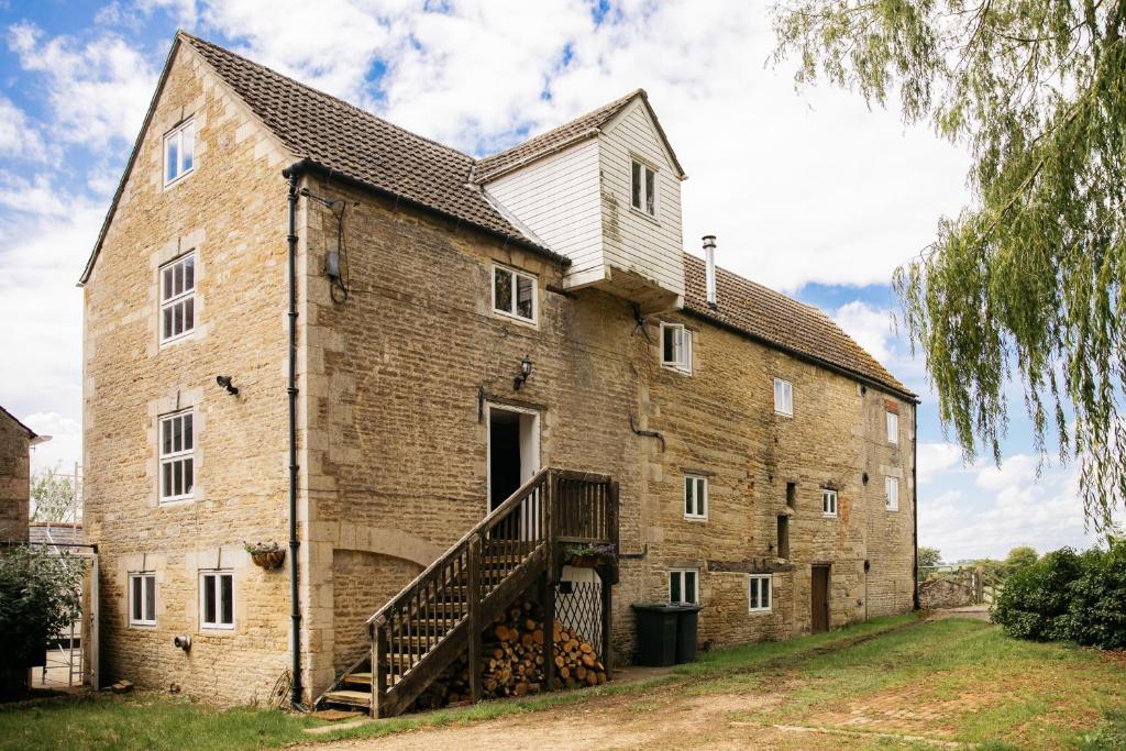 a large brick building with a staircase on the side at Fletland Mill and Holiday Hamlet - 18th century watermill, in stunning location near Stamford in Stamford