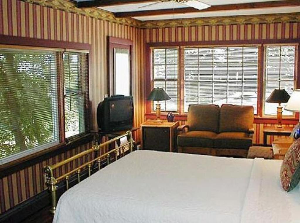 a bedroom with a bed and a tv and windows at Snug Cottage in Provincetown