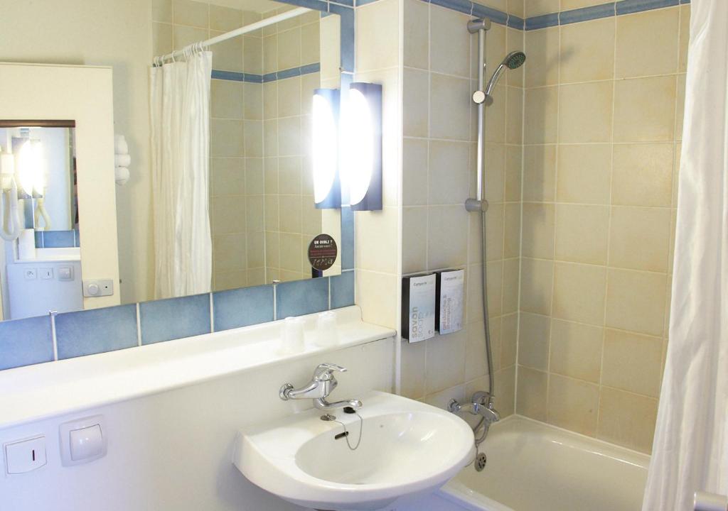 a bathroom with a sink and a mirror and a tub at Campanile Dijon Centre - Gare in Dijon