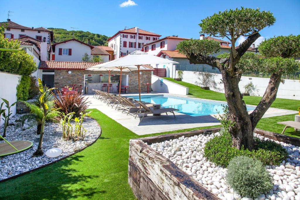 un jardin avec une piscine et un arbre dans l'établissement Hôtel Argia, à Hasparren