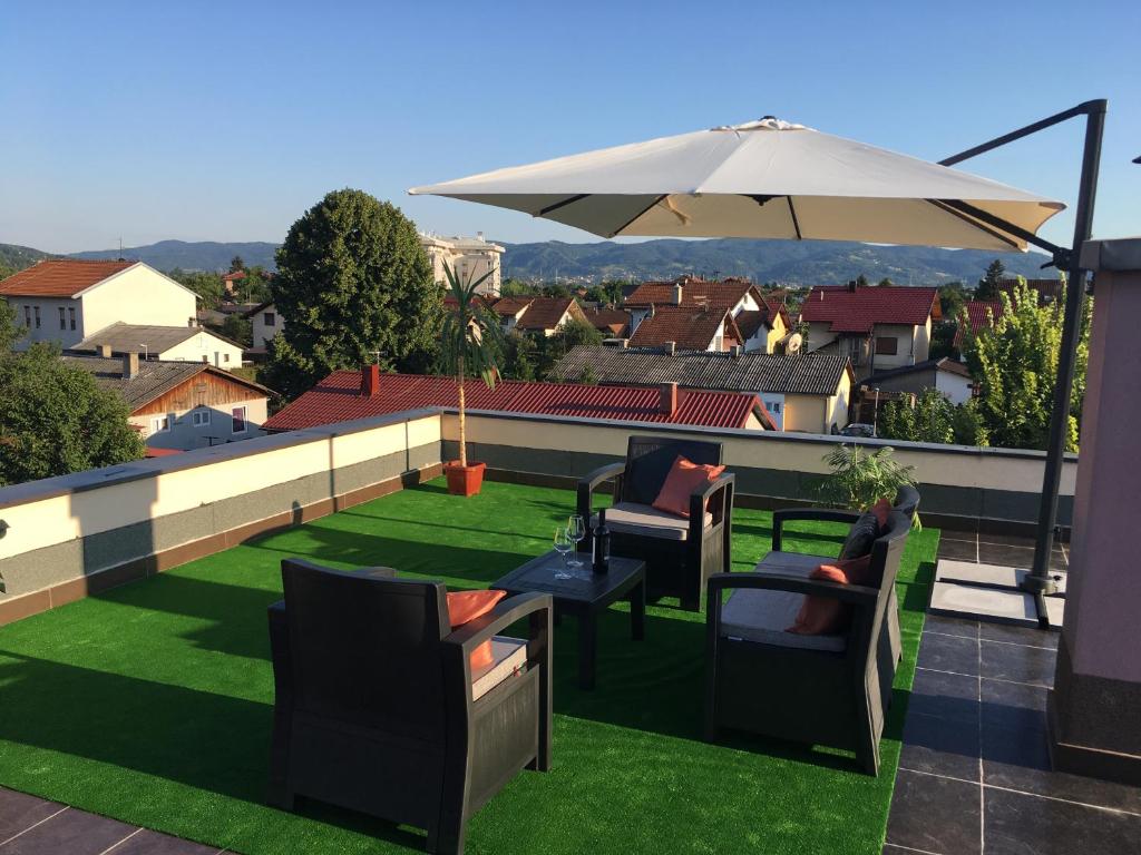 eine Terrasse mit Stühlen und einem Sonnenschirm auf dem Dach in der Unterkunft Bingo Apartments in Banja Luka