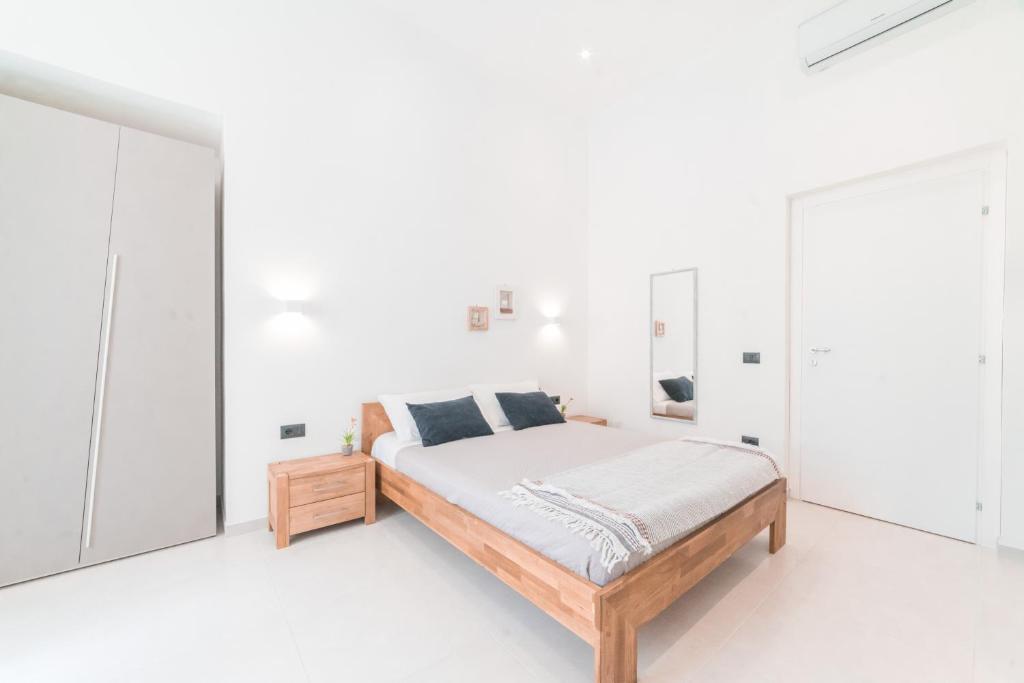 una camera bianca con letto in legno e pareti bianche di Linee Moderne Apt - Wifi - AC a Cagliari