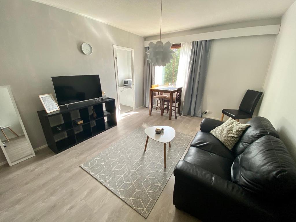 a living room with a black leather couch and a table at Cosy studio apartment - perfect for your stay in Rovaniemi! in Rovaniemi
