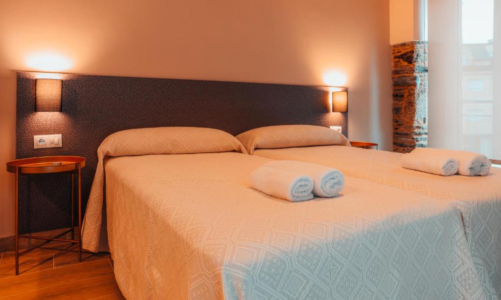 Un dormitorio con una cama grande con dos toallas encima. en Pensión A Marronda, en Baleira