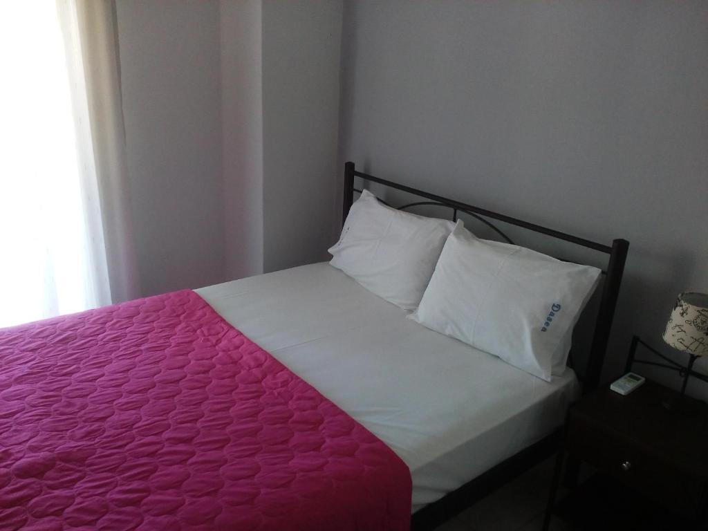 a bed with a pink blanket and white pillows at Dasea Houses in Ormos Panagias