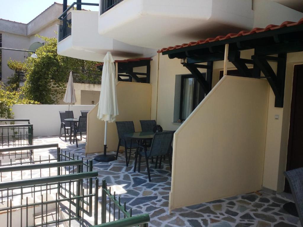a patio with chairs and tables and an umbrella at Dasea Houses in Ormos Panagias