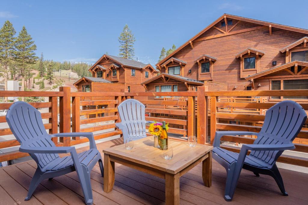 a wooden deck with three chairs and a table with flowers at Mountainside 4 in Mammoth Lakes